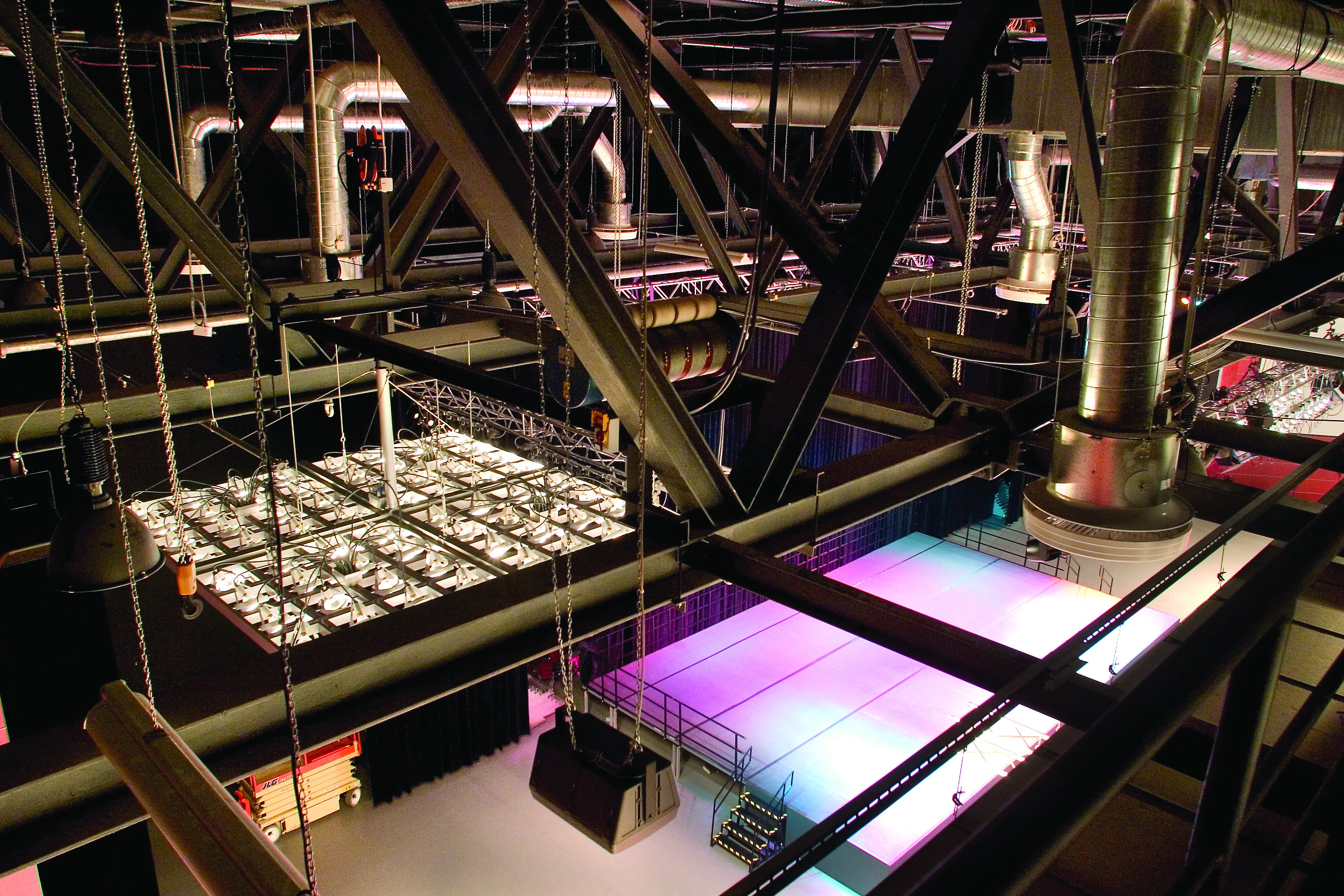 Blick von oben auf einen großen Scheinwerfer und eine beleuchtete Bühne im großen Saal des RuhrCongress Bochum