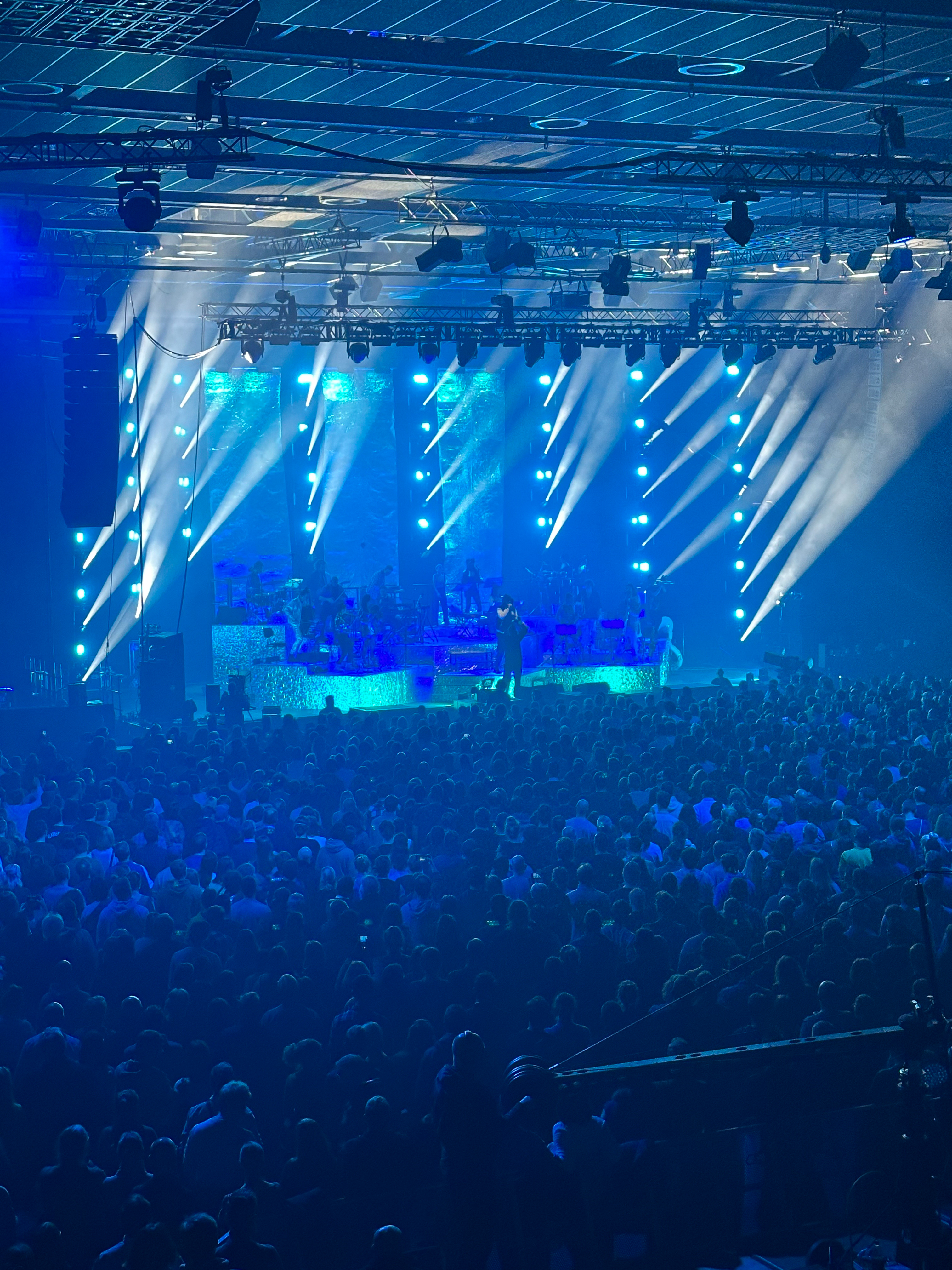 Show event at the RuhrCongress Bochum. People dancing in front of the stage, the hall is illuminated in blue.
